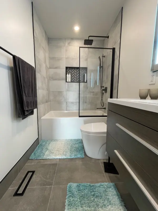 Bright modern bathroom with bathtub, glass shower and dark vanity