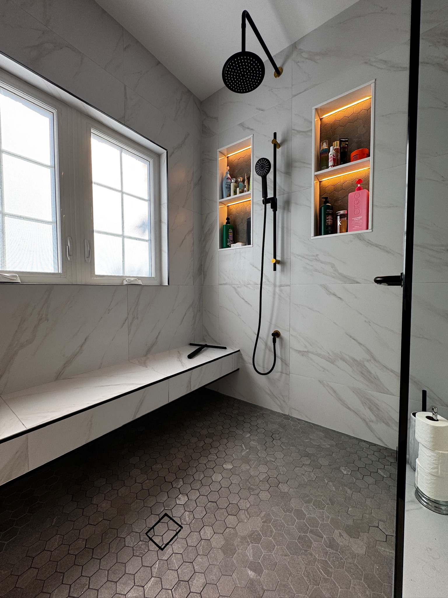 Built-in shower bench and black hexagon floor tile